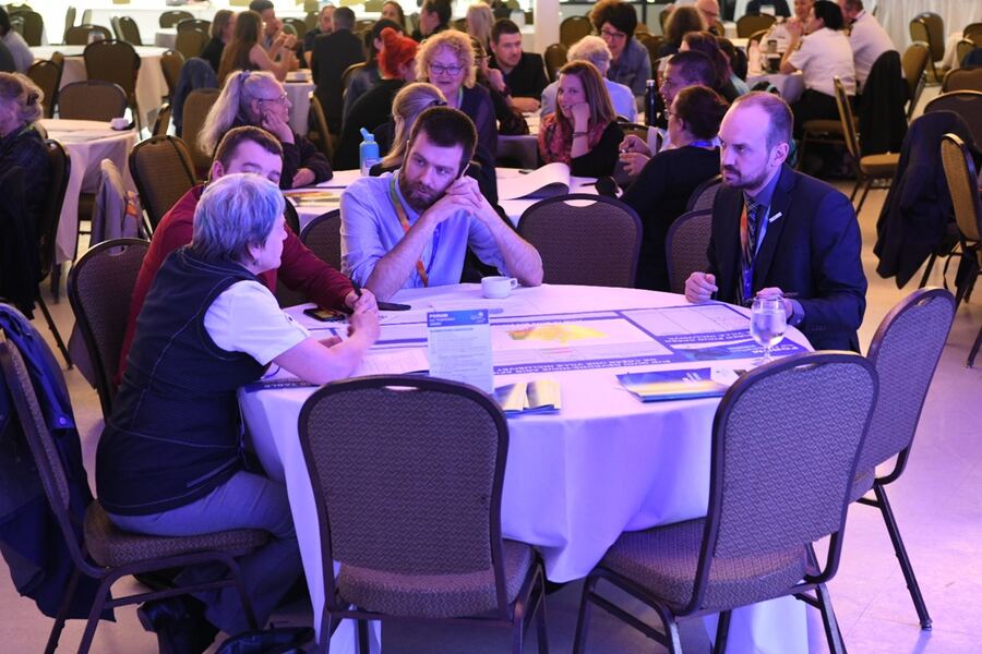 Aerial view of a forum: dozens of working tables in action